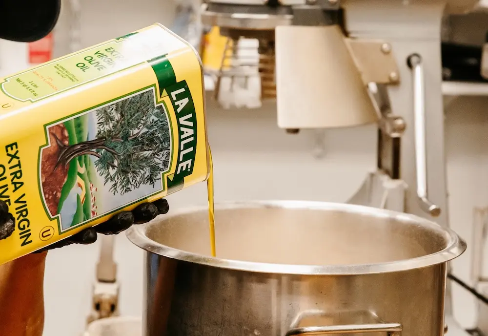 Extra virgin olive oil being poured into a mixing bowl in the Cafe Raymond kitchen